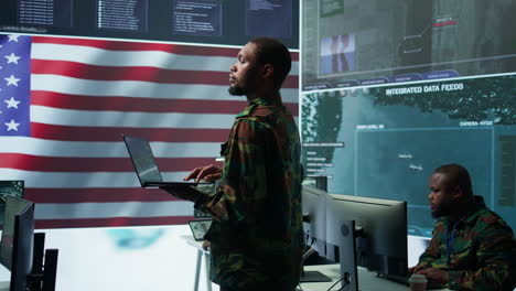 Professionals-in-US-military-uniforms-operate-computers-and-big-screen