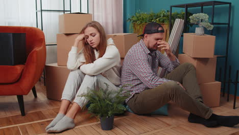 Sad-married-couple-on-floor-near-cardboard-boxes,-divorce,-long-relocation,-bankruptcy,-bank-debt