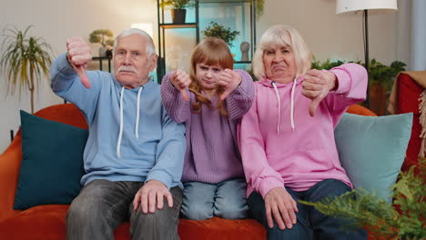 Child-girl-granddaughter-with-grandparents-showing-thumbs-down-disapproval-dissatisfied-dislike