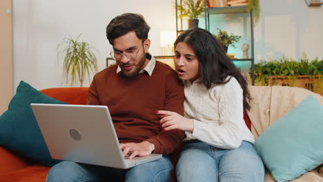 Fröhliches-Junges-Indisches-Familienpaar,-Mann-Und-Frau,-Die-Einen-Laptop-Benutzt-Und-Mit-Einer-E-Mail-überrascht-Ist,-Die-Im-Lotto-Gewinnt