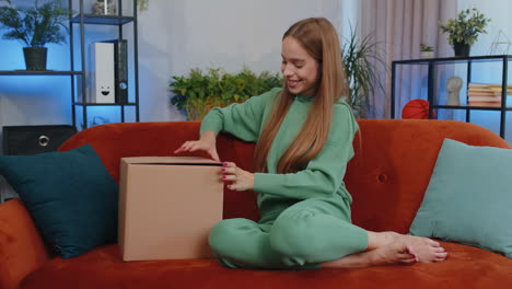 Happy-young-girl-shopper-unpacking-cardboard-box-delivery-parcel-online-shopping-purchase-at-home