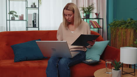 Young-business-woman-working-with-laptop-computer-and-documents,-planning-expenses-budget-at-home