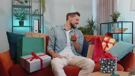 Un-Joven-Feliz-Celebrando-Una-Fiesta-De-Cumpleaños,-Pide-Un-Deseo-Soplando-Una-Vela-Encendida-En-Un-Pequeño-Pastelito