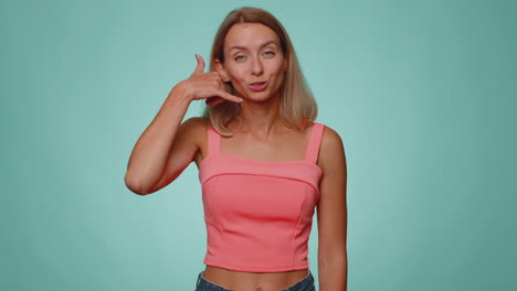 Cheerful-one-woman-in-crop-top-looking-at-camera-doing-phone-gesture-like-says-hey-you-call-me-back