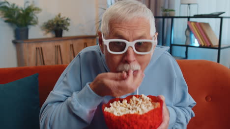 Hombre-Sentado-En-El-Sofá-Comiendo-Palomitas-De-Maíz-Y-Viendo-Interesantes-Series-De-Televisión,-Juegos-Deportivos-En-Línea-En-Casa