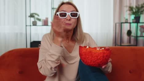 Mujer-Sentada-En-El-Sofá-Comiendo-Palomitas-De-Maíz-Y-Viendo-Interesantes-Series-De-Televisión,-Juegos-Deportivos-En-Línea-En-Casa