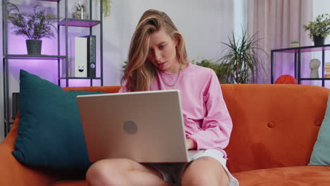 Young-woman-freelancer-sitting-on-sofa-closing-laptop-pc-after-finishing-work-in-living-room-at-home