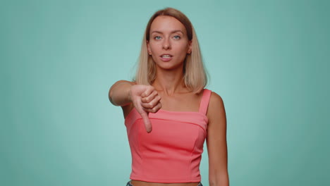 Upset-woman-in-casual-crop-top-showing-thumbs-down-sign-gesture,-disapproval,-dissatisfied-dislike