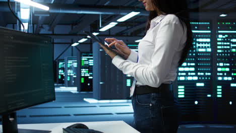 Woman-in-server-room-coding-on-tablet