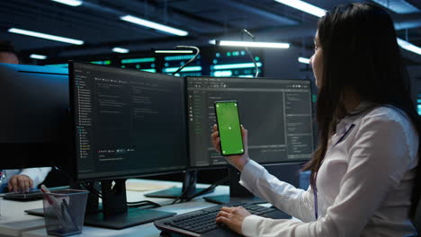 Worker-overseeing-data-center-using-green-screen-mobile-phone