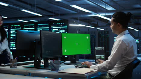 System-administrator-overseeing-data-center-using-green-screen-computer