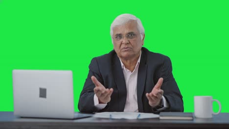 Serious-senior-Indian-businessman-talking-to-someone-Green-screen