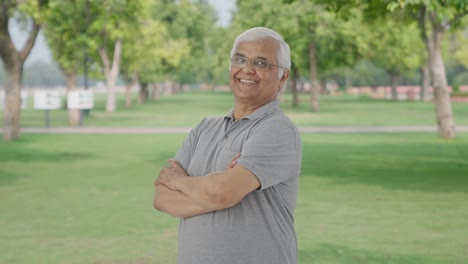 Portrait-of-Happy-Indian-old-man-standing-crossed-hands-in-park