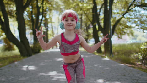 Sport-runner-child-girl-training-exercise-listening-music-on-headphones-dancing-to-camera-having-fun