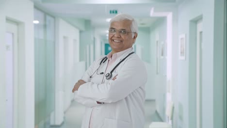 Portrait-of-Happy-Indian-senior-doctor-standing-crossed-hands