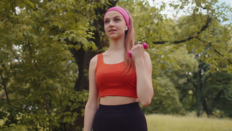 Athletic-young-sporty-fit-girl-doing-dumbbells-workout-in-sunny-park-performing-bicep-exercising