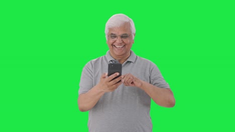 Happy-Indian-old-man-scrolling-through-phone-Green-screen