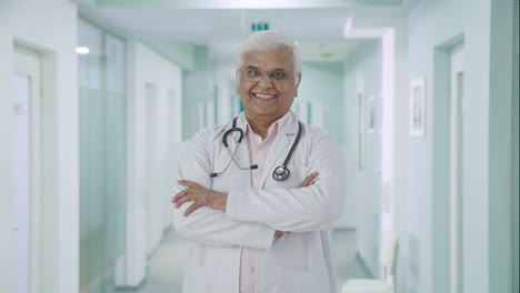 Happy-Indian-senior-doctor-standing-crossed-hands