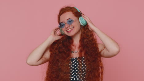 Young-redhead-woman-in-dress-listening-music-on-headphones,-dancing-disco-fooling-around-having-fun