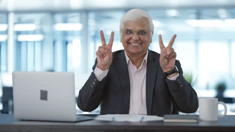 Happy-senior-Indian-businessman-showing-victory-sign