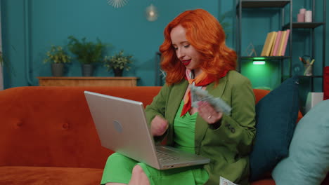 Smiling-happy-woman-counting-money-cash-and-use-laptop-pc-calculate-domestic-income-earnings-at-home