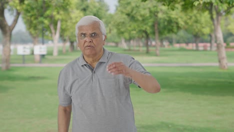 Curious-Indian-old-man-finding-something-in-park