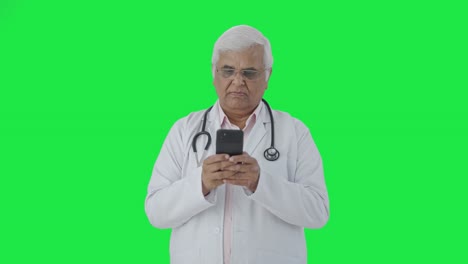 Indian-senior-doctor-chatting-with-someone-Green-screen