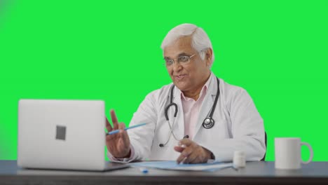 Happy-Indian-senior-doctor-consulting-patient-on-video-call-Green-screen