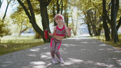 Sport-runner-jogger-child-girl-listen-bluetooth-music-speaker-dancing-to-camera-having-fun-in-park