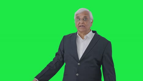 Indian-senior-journalist-pointing-at-green-screen-and-reading-news