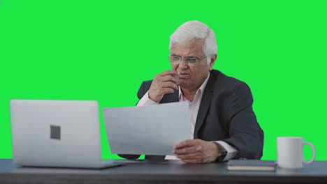 Confused-Indian-senior-manager-reading-business-reports-Green-screen