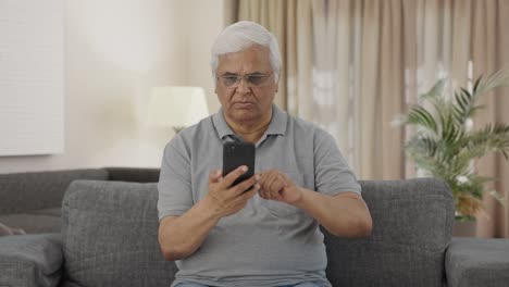 Indian-old-man-scrolling-through-phone