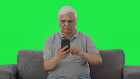 Indian-old-man-scrolling-through-phone-Green-screen