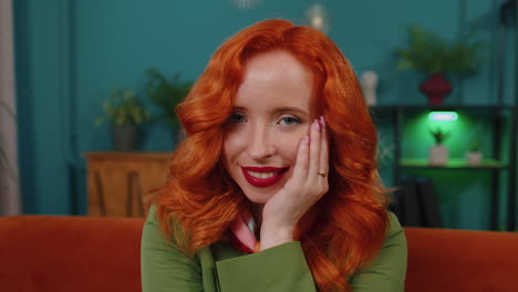 Close-up-of-happy-beautiful-teenager-redhead-ginger-woman-smiling-looking-at-camera-at-home-on-couch