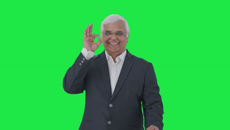 Happy-Indian-senior-journalist-showing-okay-sign-Green-screen