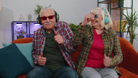 Joyful-senior-grandparents-man-woman-listening-music-dancing-disco-fooling-around-having-fun-at-home