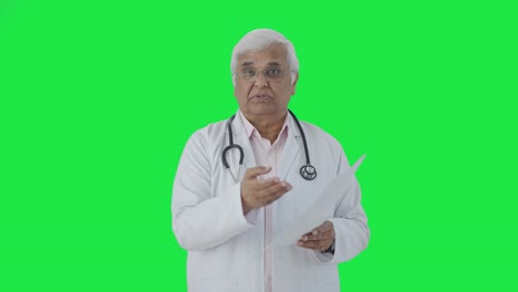 Médico-Senior-Indio-Explicando-Informes-De-Salud-A-La-Pantalla-Verde-Del-Paciente.