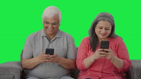 Happy-Old-Indian-couple-busy-in-their-phones-Green-screen