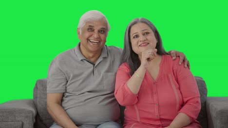 Happy-and-cheerful-Indian-old-couple-watching-TV-Green-screen