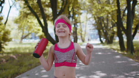 Sport-runner-jogger-child-girl-listen-bluetooth-music-speaker-dancing-having-fun-walking-in-park