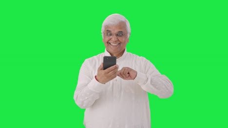 Cheerful-Indian-old-man-scrolling-through-phone-Green-screen