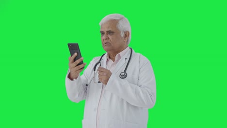 Indian-senior-doctor-consulting-patient-over-video-call-Green-screen