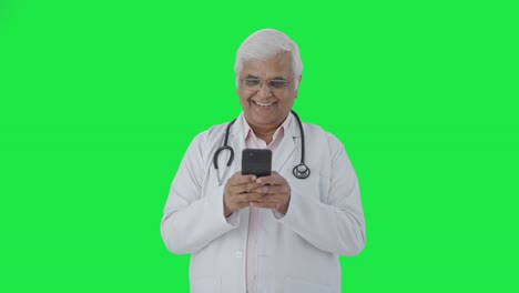 Happy-Indian-senior-doctor-chatting-with-someone-Green-screen