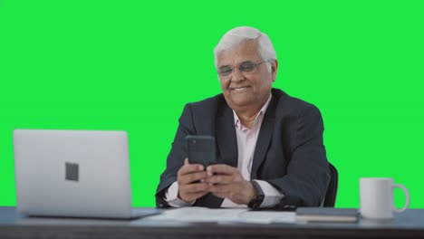 Happy-Indian-senior-manager-using-mobile-phone-Green-screen