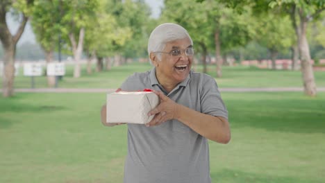 Happy-Indian-old-man-receiving-a-gift-in-park