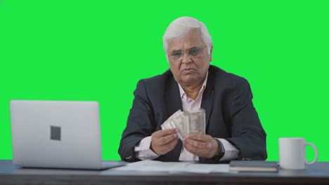 Confused-Indian-senior-businessman-counting-money-Green-screen