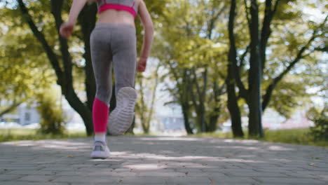 Rear-view-of-athletic-fit-sport-jogger-teen-girl-training-marathon-run,-running-forward-on-road