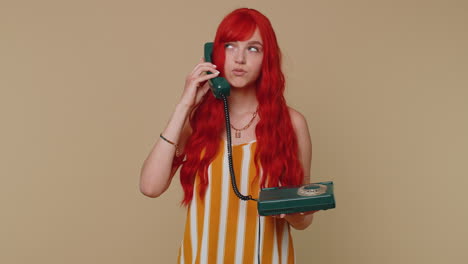 Crazy-redhead-girl-talking-on-wired-vintage-telephone-fooling,-making-making-playful-silly-faces