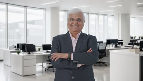 Happy-Indian-senior-businessman-standing-crossed-hands