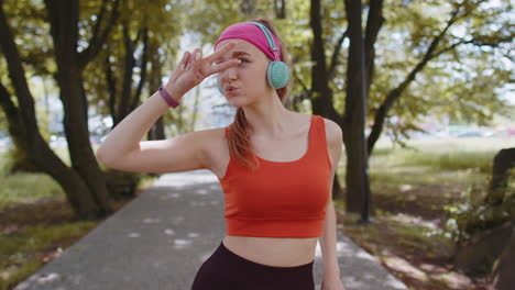 Corredor-Deportivo-Chica-Bonita-Ejercicio-De-Entrenamiento-Escuchando-Música-Con-Auriculares-Bailando-Divirtiéndose-En-El-Parque